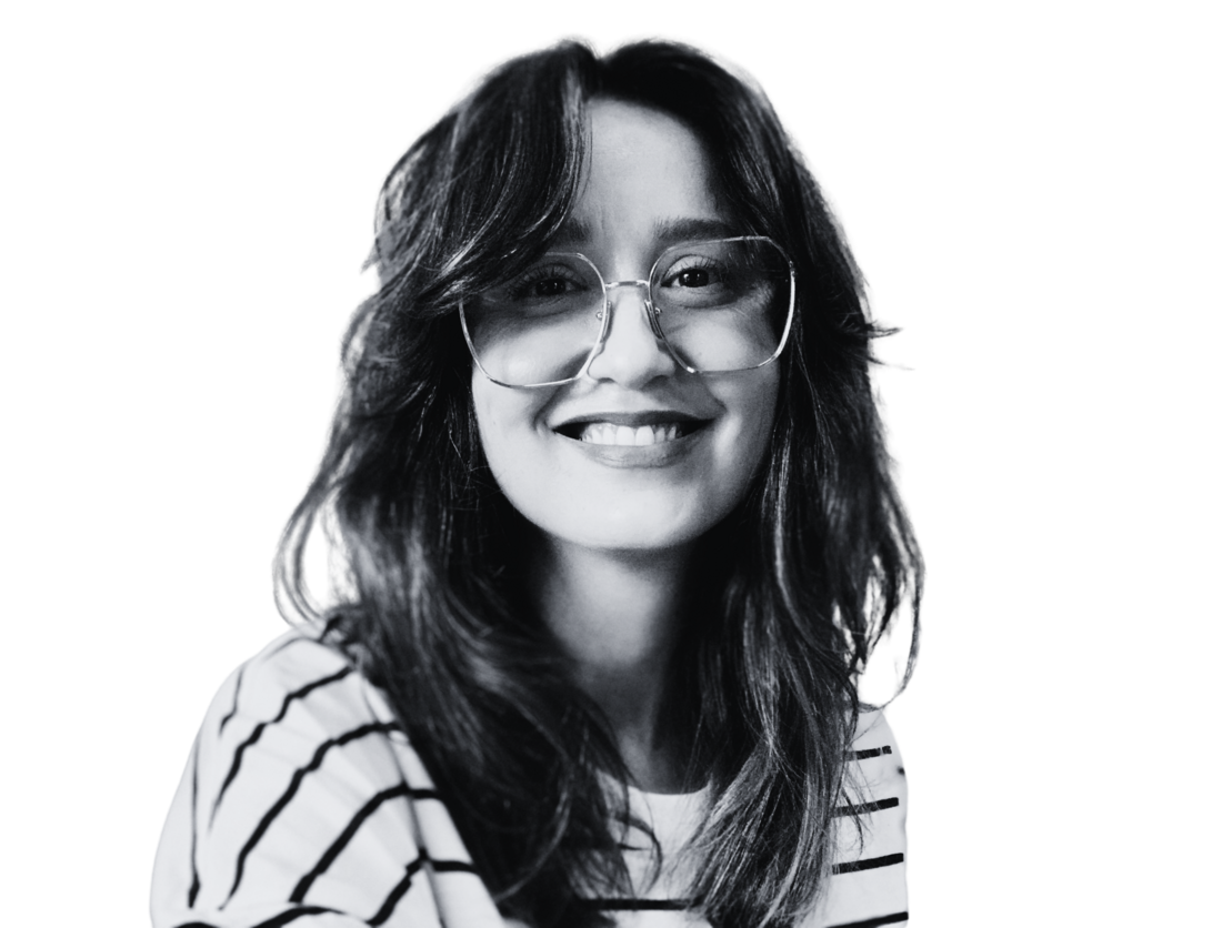 Monalisa Vasconcelos sorrindo, de óculos, blusa listrada